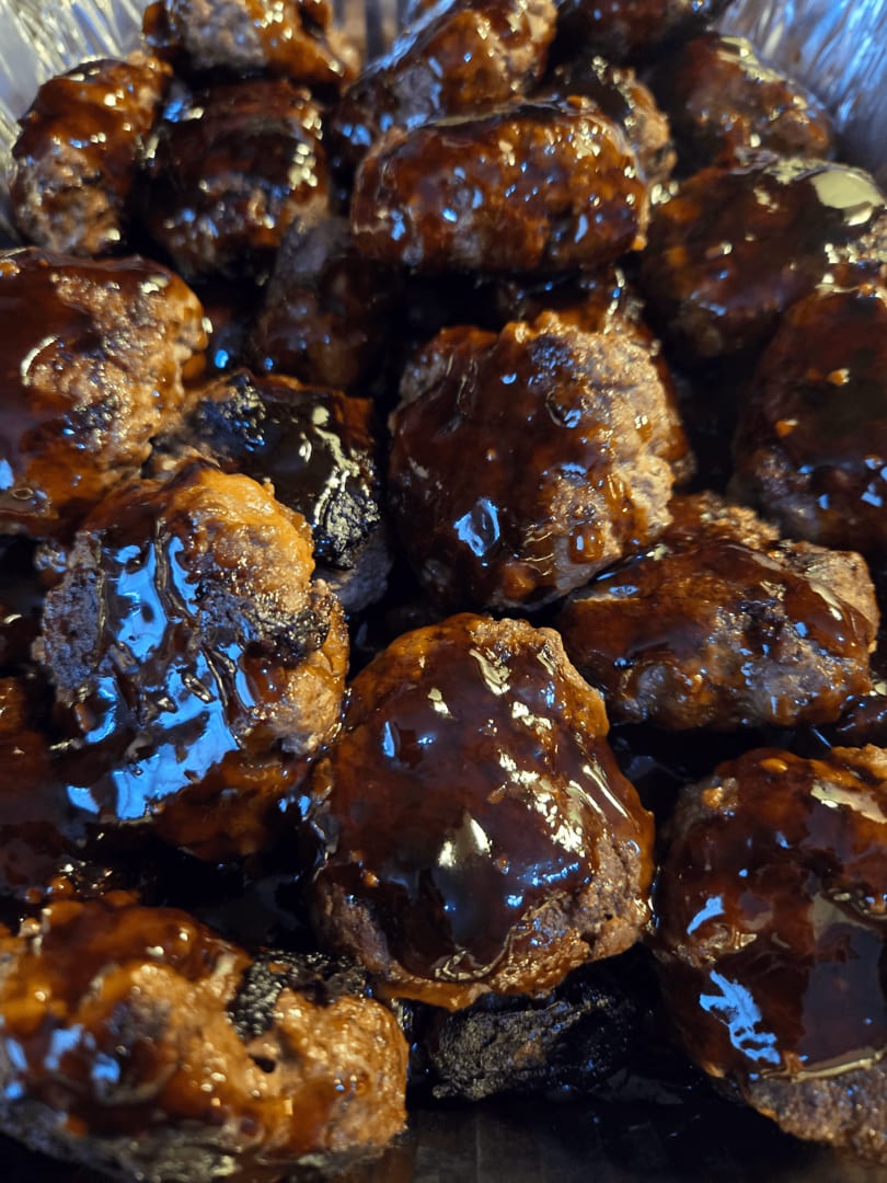 Close-up of Mama Dukes Hawaiian Barbeque meatballs, glistening with a rich, dark sauce.